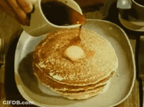 A Person Pouring Syrup On A Stack Of Pancakes With Butter GIF