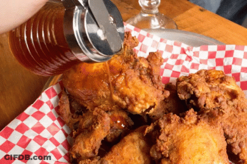 A Person Pouring Syrup Over Fried Chicken On A Checkered Napkin GIF