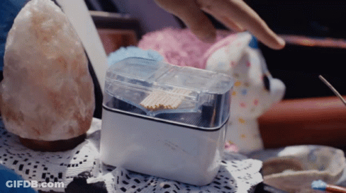 A Person Reaches For A Container Of Matches On A Table With A Stuffed Animal In The Background GIF