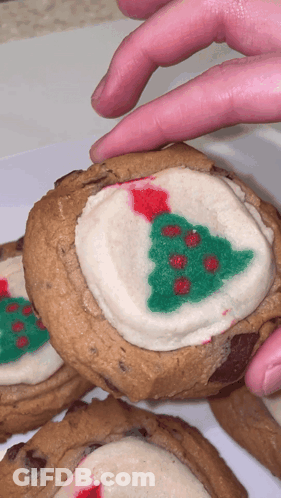 A Person Reaches For A Cookie With A Christmas Tree On It GIF