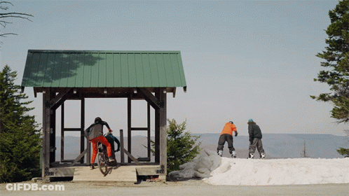A Person Riding A Bike In Front Of A Green Roof GIF