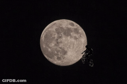 A Person Riding A Bike In Front Of The Moon GIF