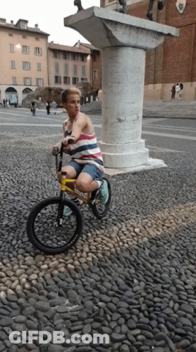 A Person Riding A Bike On A Cobblestone Street GIF