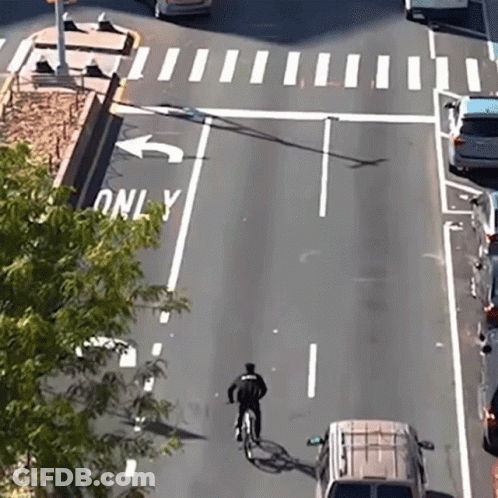 A Person Riding A Bike On A Street With A Sign That Says Only On It GIF