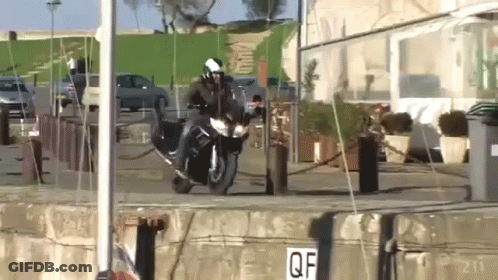 A Person Riding A Motorcycle In Front Of A Building With A Sign That Says Qf GIF