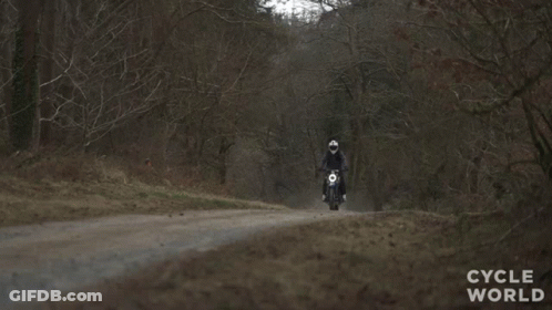 A Person Riding A Motorcycle On A Dirt Road With The Words Cycle World Visible GIF