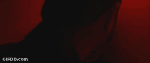 A Person 'S Arm Is Visible In A Dark Room With A Red Light Behind Them . GIF