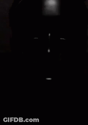 A Person 'S Face Is Visible In The Dark With A Light Shining On It . GIF