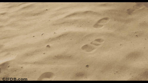 A Person 'S Feet Are Covered In Sand While Walking On A Sandy Beach . GIF