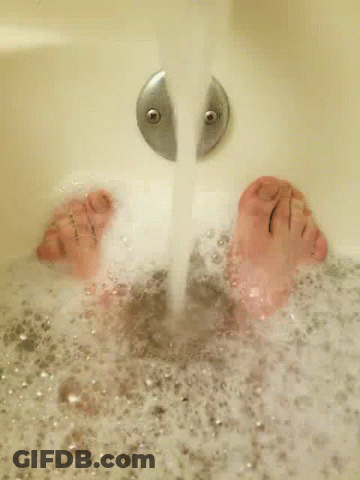 A Person 'S Feet Are Floating In A Bathtub Filled With Foam . GIF