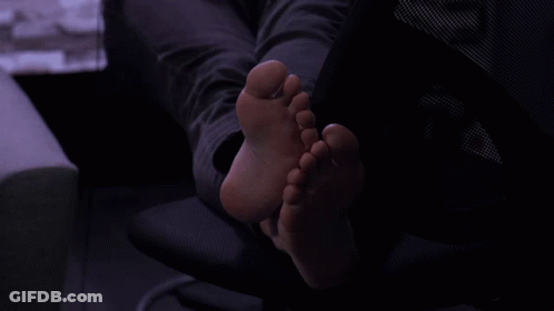 A Person 'S Feet Are Laying On A Chair In A Dark Room GIF