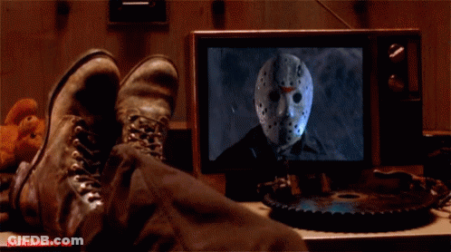 A Person 'S Feet Are Laying On A Table In Front Of A Tv Screen With Jason Voorhees On It GIF
