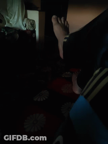A Person 'S Feet Are Standing On A Red And Black Blanket With Flowers On It GIF
