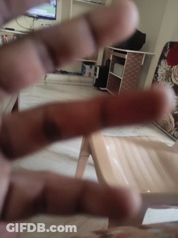 A Person 'S Fingers Are Visible In A Blurry Photo With A Chair In The Background GIF