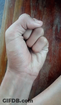 A Person 'S Fist Is Against A Wooden Table GIF
