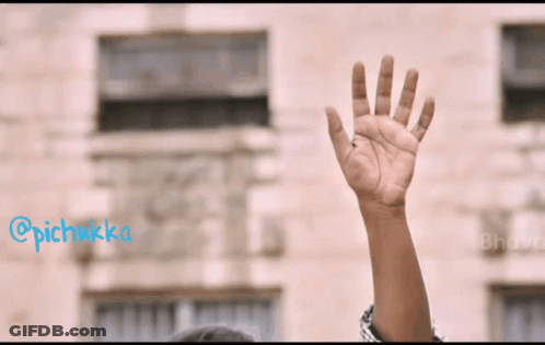 A Person 'S Hand Is Raised In The Air In Front Of A Building With The Hashtag @Pichikka GIF