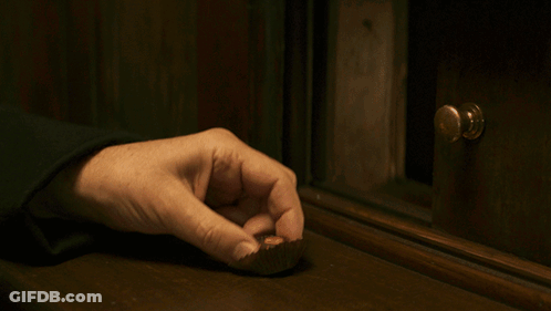 A Person 'S Hand Is Reaching For A Piece Of Chocolate On A Wooden Table GIF