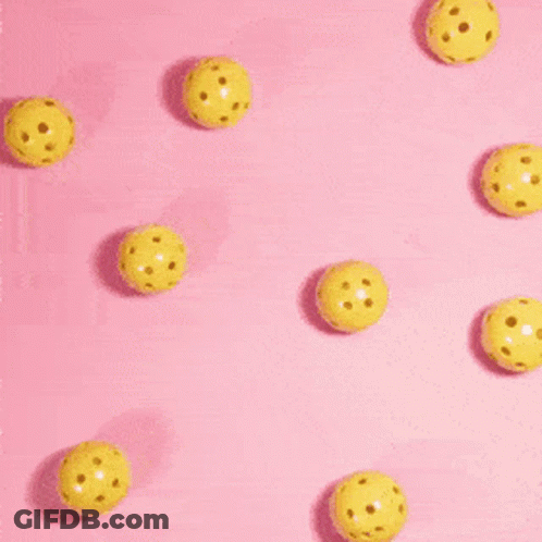 A Person 'S Hand Is Reaching For A Yellow Ball On A Pink Background . GIF
