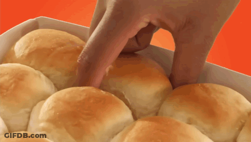 A Person 'S Hand Is Reaching Into A Box Of Rolls GIF