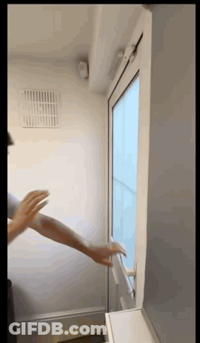 A Person 'S Hand Is Reaching Out To Open A Window GIF