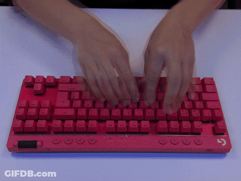 A Person 'S Hands Are Typing On A Red Keyboard That Has The Shift Key On The Bottom Right GIF