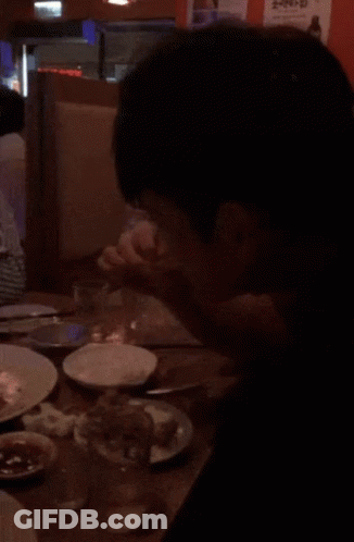 A Person Sitting At A Table With Plates Of Food And A Sign That Says ' Ae ' On It GIF