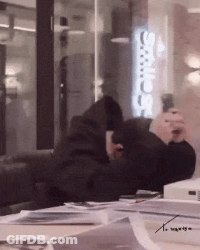 A Person Sitting In Front Of A Sign That Says ' Adidas ' GIF