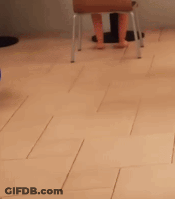 A Person Sitting On A Stool On A Tiled Floor GIF