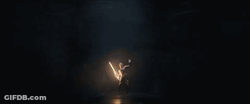 A Person Standing In A Dark Room With A Light Coming Out Of Their Hands GIF