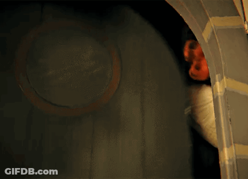 A Person Standing In A Dark Room With A Red Mask On Their Head GIF