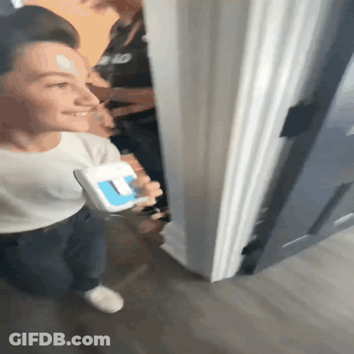 A Person Standing In A Doorway Holding A Box That Says U On It GIF