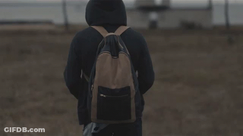 A Person Standing In A Field Holding A Knife With A Building In The Background GIF