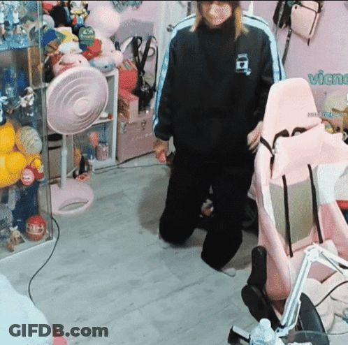 A Person Standing In A Room With A Pink Chair And A Sign That Says Vichu GIF