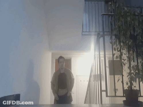 A Person Standing In Front Of A Balcony With A Plant GIF
