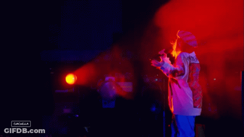 A Person Standing In Front Of A Microphone With The Word Cancella On The Bottom Right GIF