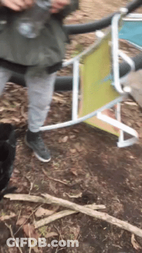 A Person Standing Next To A Folding Chair That Has A Yellow Back GIF