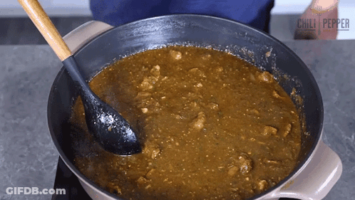A Person Stirring A Pot Of Chili Pepper Sauce With A Black Spoon GIF