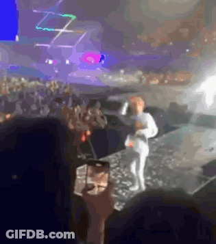 A Person Taking A Picture Of A Person On Stage With A Cell Phone GIF