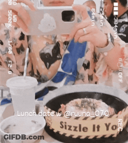 A Person Taking A Picture Of A Plate Of Food With A Sign That Says Sizzle It You On It GIF