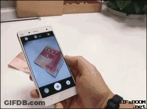 A Person Taking A Picture Of A Stack Of Money With A Cell Phone GIF