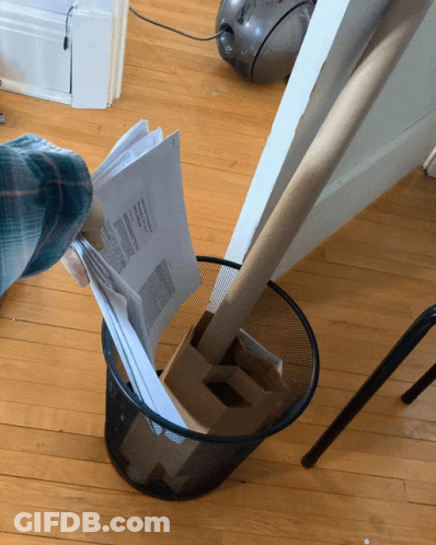 A Person Throws A Piece Of Paper Into A Trash Can That Says ' Papers ' On It GIF