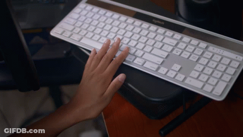 A Person Typing On A Logitech Keyboard On A Wooden Desk GIF