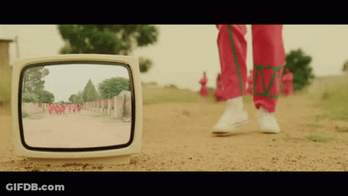 A Person Walking Down A Dirt Road Is Reflected In A Television Screen GIF