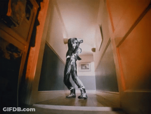 A Person Walking Down A Hallway With A Picture On The Wall GIF