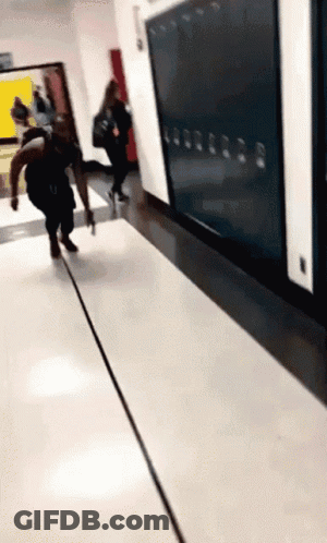 A Person Walking Down A Hallway With A Row Of Lockers Behind Them GIF