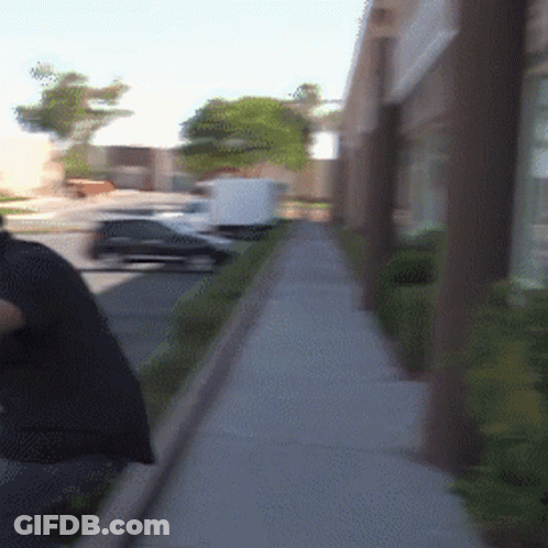 A Person Walking Down A Sidewalk With A Bag On Their Back GIF