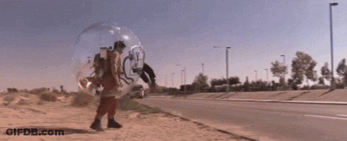 A Person Walking In A Clear Bubble On The Side Of The Road GIF
