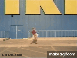 A Person Walking In Front Of A Large Yellow Sign That Says Ikea GIF