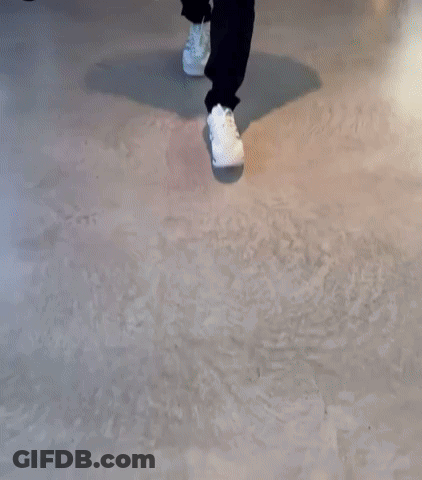 A Person Walking On A Concrete Floor Wearing White Shoes GIF