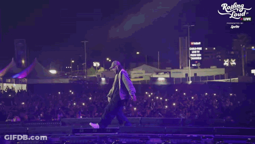 A Person Walking On A Stage With A Rolling Loud Logo In The Background GIF